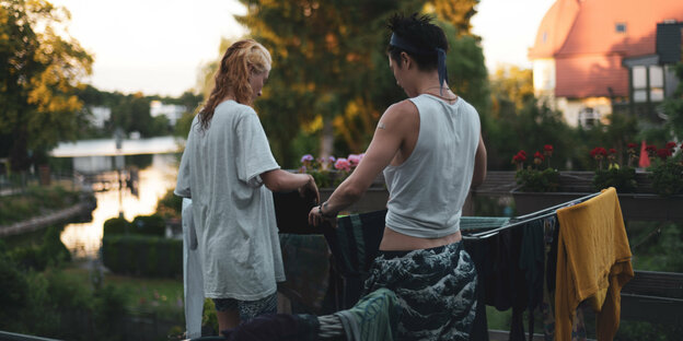 Ein queeres Paar hängt zuhause zusammen Wäsche auf
