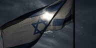 Eine israelische Flagge weht und verdunkelt dabei die Sonne dahinter