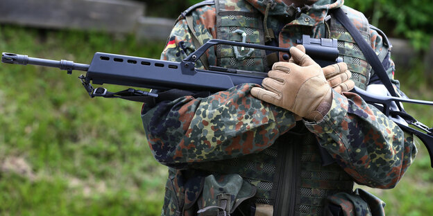 Soldat hält ein Sturmgewehr der Firma Heckler und Koch in den Armen Soldat hält ein Sturmgewehr der Firma Heckler und Koch in den Armen