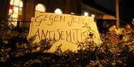 Ein Pappschild steckt in einem Busch vor einer Synagoge am Fraenkelufer, darauf steht: "Gegen jeden Antisemitismus"