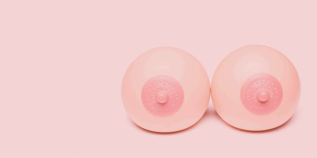 Zwei Bälle, die wie weibliche Brüste aussehen vor rosa Hintergrund