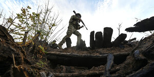 Ein ukrainischer Soldat geht mit Waffe durchs Gelände