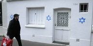 Auf einer weißen Hauswand sind drei blaue Davidsterne gesprayt