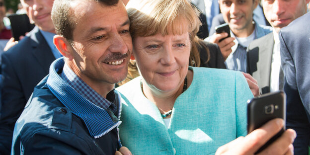 Frau Merkel und ein Flüchtling machen ein Selfie Frau Merkel und ein Flüchtling machen ein Selfie