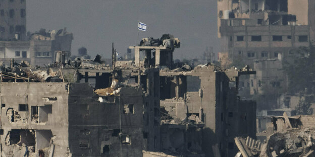 Destroyed buildings with an Israeli flag flown on them.