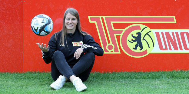Coach Eta with a ball in her hand sitting in front of a board with the inscription 1. FC Union