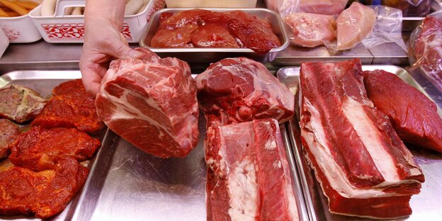 Verschiedenes Fleisch in der Theke. Eine Hand greift zu. Verschiedenes Fleisch in der Theke. Eine Hand greift zu.