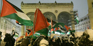 Die propalästinenische Demo "Stoppt den Krieg!" mit vielen Fahen vor einem historisch belasteten Ort, der verschneiten Feldherrnhalle in München, am 24.11. 2023