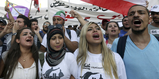Junge Protestierende vor einer Fahne des Libanon. Junge Protestierende vor einer Fahne des Libanon.