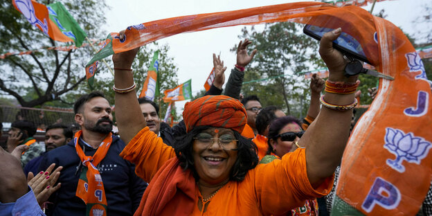 Eine Frau in orange gekleidet schwingt einen Schal für die BKP Partei