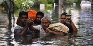 Menschen überqueren eine überflutete Straße in Indien