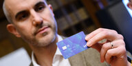 Hannovers Oberbürgermeister Belit Onay (Grüne) hält eine blaue Visa-Karte in die Kamera.