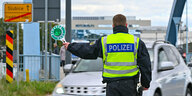 Grenzkontrolle , Polizist von hinten hält ein Auto an, deutscher Grenzpfosten