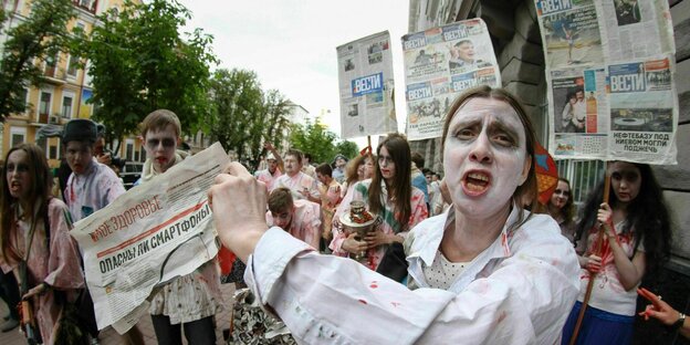 Aktivisten, verkleidet als Zombies mit der aktuellen Ausgabe von Vesti im Jahr 2015