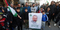 Kinder halten ein Plakat mit dem Foto des verstorbenen stellvertretenden Hamas-Führers Saleh al-Arouri , umeringt von trauernden Männern