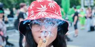 Eine junge Frau raucht einen Joint auf einer Hanfparade.