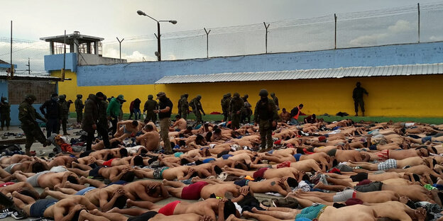 Many people lay on the ground in their underwear, while armed men surrounded them.