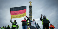 Landwirte protestieren mit einer Deutschlandfahne mit der Aufschrift ·Unser Land zuerst· vor der Siegerssäule