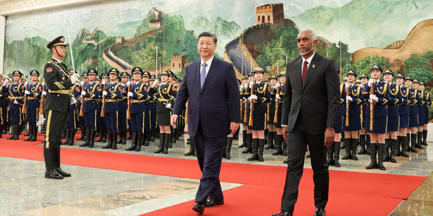 The presidents of Maldives and China walk on a red carpet in front of a military formation