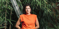 Effekbewusst: Katrin Gebbe in orangem Shirt vor dem Grün von Pflanzen