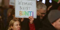 Junge Frau hält Schild hoch , auf dem steht "Weimar bleibt bunt"