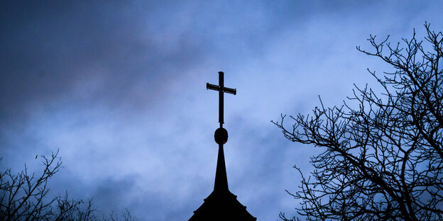 Eine Kirchturmspitze im dunklen Abendhimmel