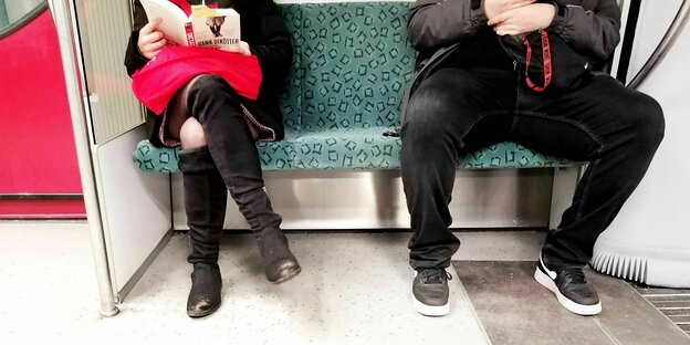 A woman with her legs crossed sits next to a collapsed man on the subway.