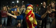 Tag des Referendums in Barcelona, eine junge Frau, die ihr Gesicht mit der katalonischen Flagge verhüllt, zeigt den Stinkefinger