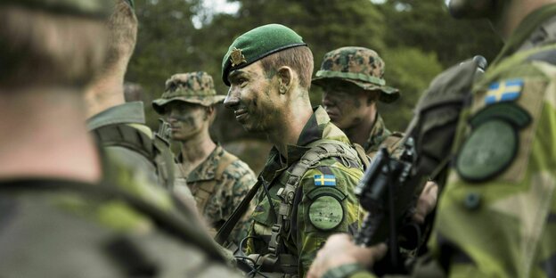 Swedish soldiers in camouflage uniforms and painted faces.