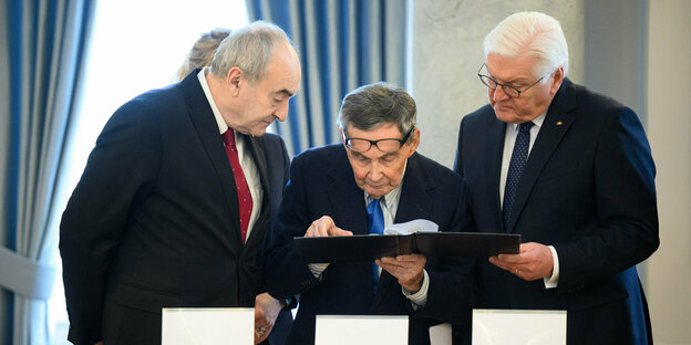 Zygmunt Stepinski, Marian Turski (m) and Frank-Walter Steinmeier look together at historical photographs of the Warsaw Ghetto