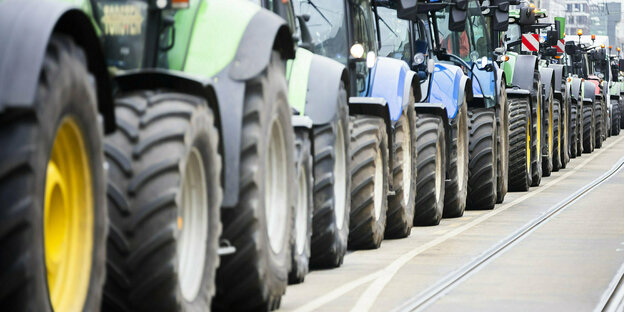 Tractors stand in a row on the street during a protest.