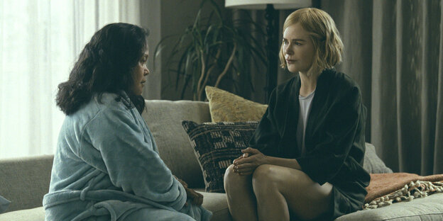 A woman, Nicole Kidman, sitting on a couch with another woman in a bathrobe.