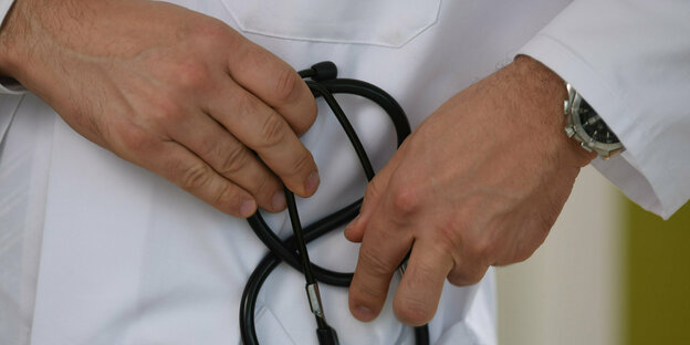 A doctor holds a stethoscope in his hand.