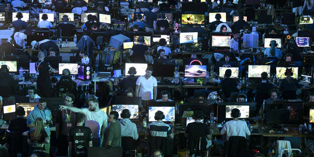 Viele Gamer spielen Computerspiele auf ihren Rechnern während einem Festival für Gaming, sie sitzen dicht gedränt in langen Reihen an ihren Rechnern