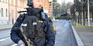Ein bewaffneter Polizist steht auf einer Straße.