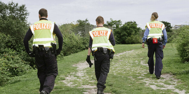 Three police officers walk along a park path.