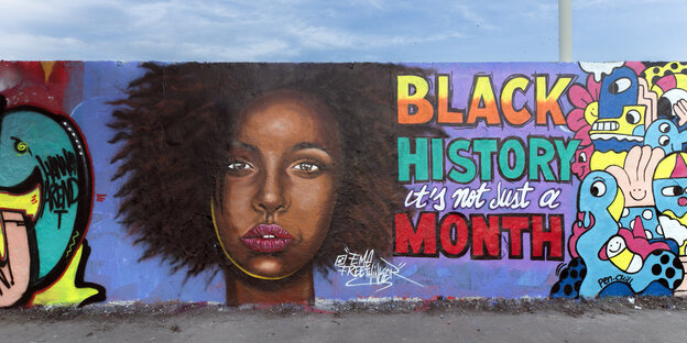 Graffiti on a wall with the face of a black woman and the note: Black History is not just a month.