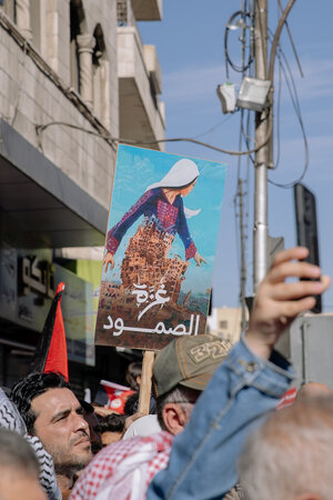 Demonstrierende Menschen, ein Plakat, auf dem eine Person zu sehen ist, die ein Kleid mit Tatreez trägt