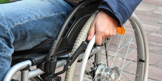 A man walks on cobblestones in his wheelchair.