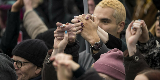 Participants in a demonstration hold hands.
