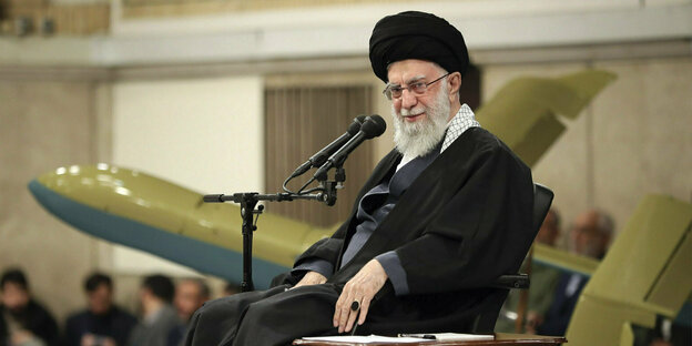 Supreme Leader Ayatollah Ali Khamenei sits next to a model of a fighter jet during a meeting with the Army Air Force.