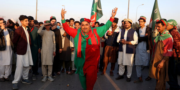People, one of them wearing PTI colors, dance in the street