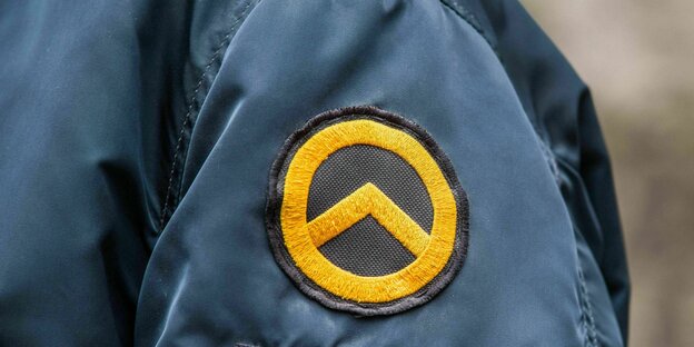 Logo of the identitarian movement: a yellow circle with a two-legged triangle facing upwards