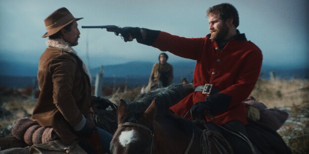 Ein Mann auf einem Pferd zielt mit Pistole auf einen anderen Mann, der direkt vor ihm steht. Der Arm mit der Wadffe ist gestreckt. Die Waffe endet direkt im Gesicht.