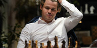 Magnus Carlsen sitzt vor einem Schachbrett.