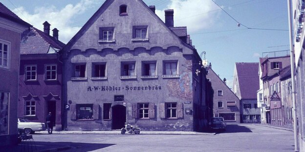 Ansicht von Schongau ind en 60er Jahren, stille Gassen, ein Wirtshaus, davor parkt ein Moped, das Foto hat einen rötlichen Stich
