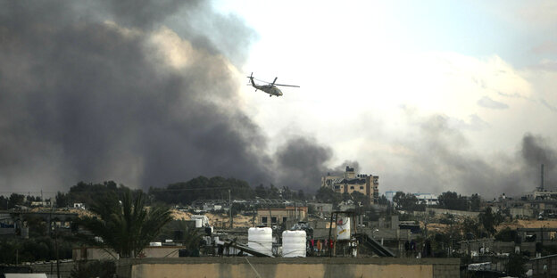 Ein israelischer Helikopter fliegt über Chan Junis. Rauschschwaden steigen über der Stadt hoch