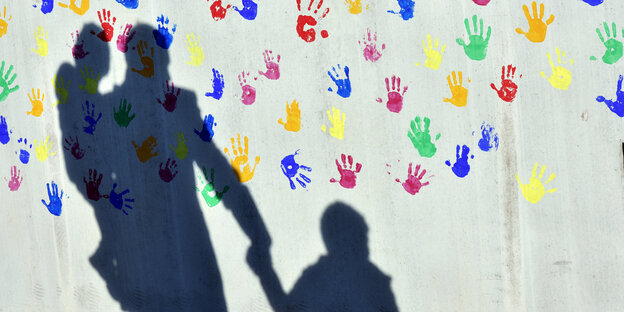Schatten einer Familie an einer bemalten Wand Schatten einer Familie an einer bemalten Wand