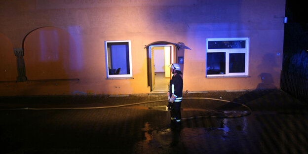 Ein Feuerwehrmann steht in der Nacht vor dem Haus auf welches der Anschlag verübt wurde Ein Feuerwehrmann steht in der Nacht vor dem Haus auf welches der Anschlag verübt wurde