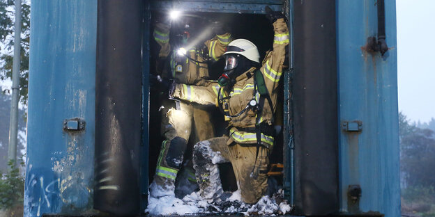Zwei Feuerwehrleute drängen sich in das brennende Zugabteil Zwei Feuerwehrleute drängen sich in das brennende Zugabteil